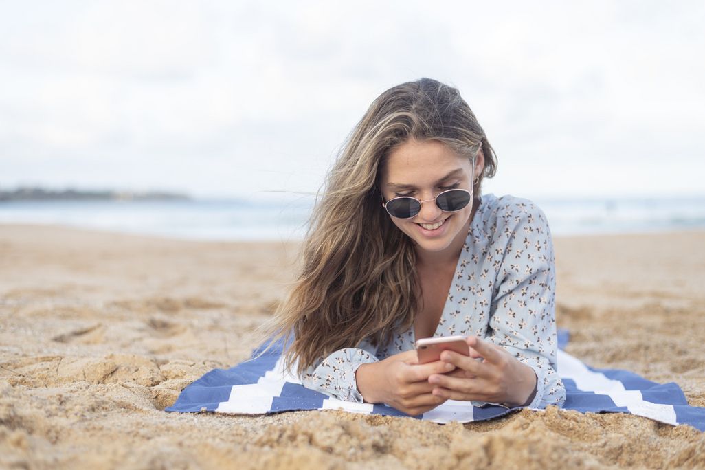 Frau mit Smartphone am Strand