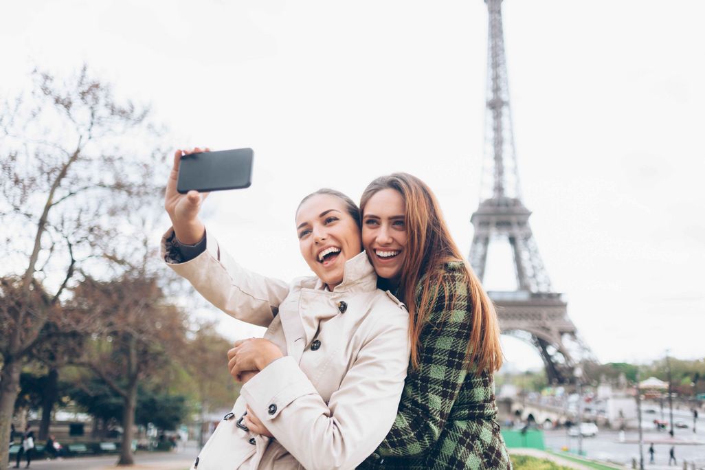 Zwei Frauen fotografieren sich vor dem Eiffelturm