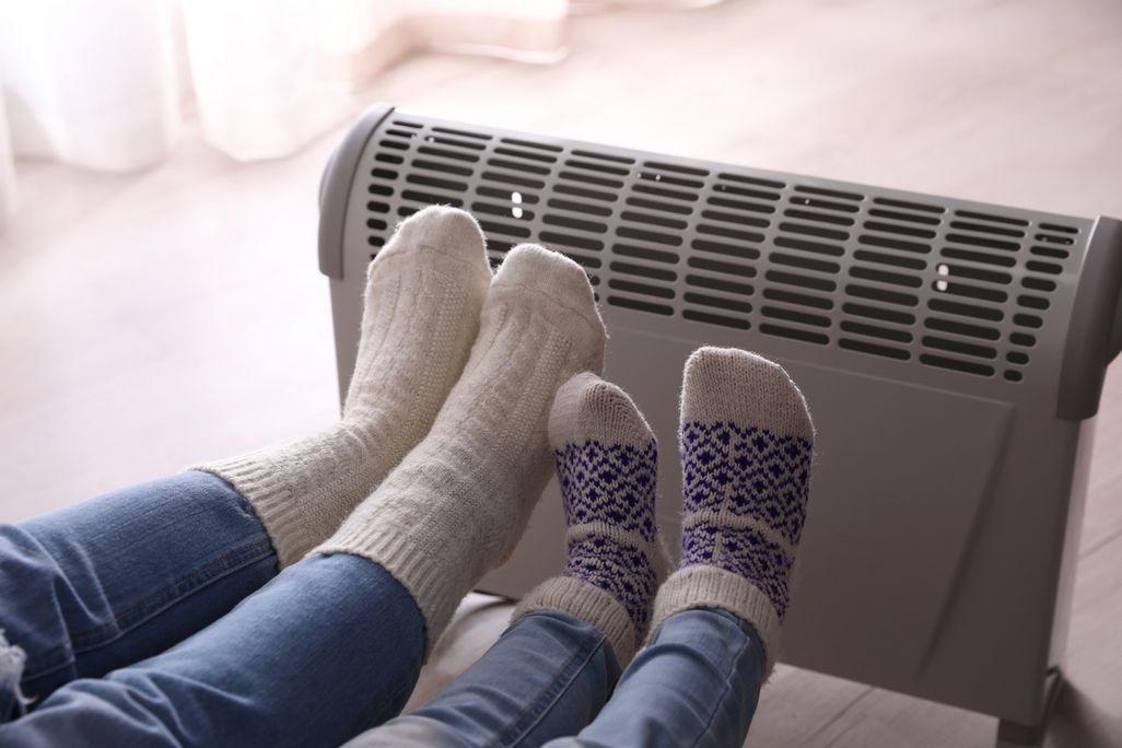 Füße suchen Wärme bei einer Konvektorheizung