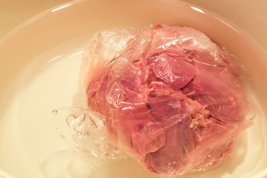 Tiefgefrorenes Fleisch i einer Wasserschüssel