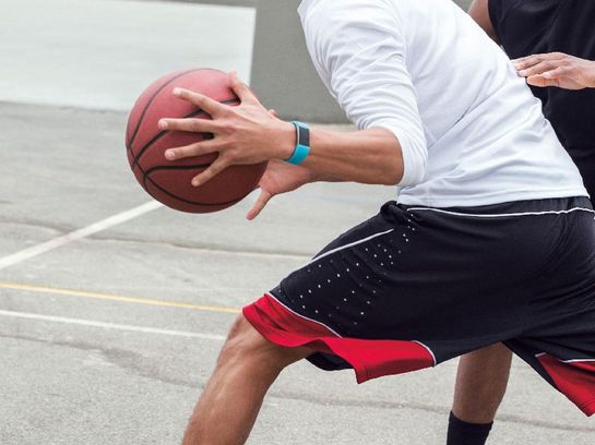 Zwei Männer spielen Basketball, einer trägt das Fitbit "Charge 2"