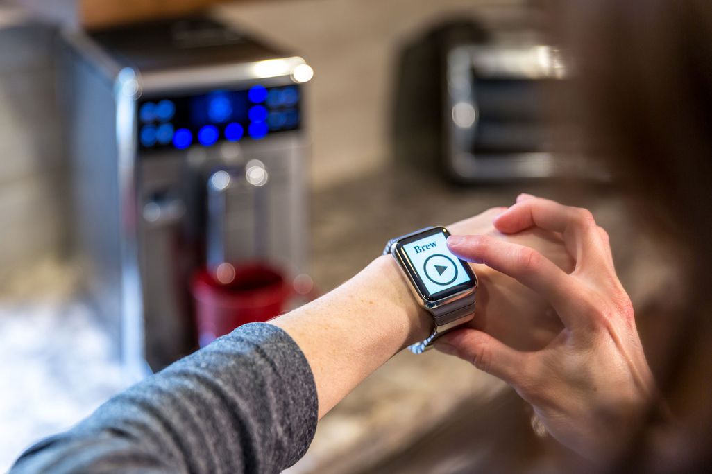Ein Mann bedient mit seiner Smart Watch die Kaffeemaschine